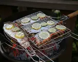 Grillad fisk med citron- och limeklyftor på en kolgrill. Doften av sommar och god mat sprider sig.