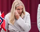 Kronprinsessan Mette-Marit med syrgasgrimma, en påminnelse om hennes sjukdom, håller en norsk flagga.