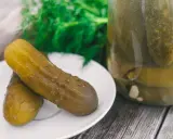 Dwa ogórki kiszone na talerzyku, obok słoik pełen kiszonków. Zastanawiasz się, dlaczego ogórki kiszone są puste w środku? To proces fermentacji!