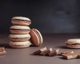 Une pile de macarons de Noël à la garniture chocolatée, avec des morceaux de chocolat sur le côté.