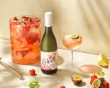 En stor bålskål fylld med jordgubbar och is, en flaska vitt vin och en cocktail med passionsfrukt. Perfekt för en somrig drink med vitt vin.