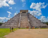 Majestatyczna piramida w Chichen Itza, z turystami podziwiającymi jej piękno na tle błękitnego nieba.