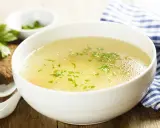 Aromaticzny rosół z perliczki, ozdobiony natką pietruszki, podany z kromką chleba. Idealny na chłodne dni.