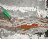 Espátula verde sobre pared agrietada con restos de pintura, como si se estuviera retirando el grout.