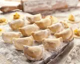 Gotujesz pierogi? Zobacz, jaka mąka do pierogów będzie najlepsza! Na zdjęciu świeżo lepione pierogi, wałek i rozsypana mąka.