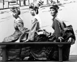 Trzy kobiety w historycznych strojach siedzą na ławce. Czy jedna z nich to guwernantka, która pilnuje porządku?
