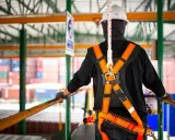 Trabajador con arnés de seguridad naranja y blanco, listo para trabajar en altura. La vida útil de un arnés de seguridad depende de su uso y mantenimiento.