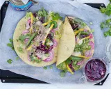 Två läckra tonfisk wraps fyllda med grönsaker, rödlök och en krämig sås. En burk med rödkålssallad står bredvid.