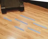 Marcando con cinta azul las áreas del suelo laminado que necesitan reparar.