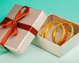 Scatola regalo aperta con bracciali dorati e rossi. Come capire se un bracciale è oro? Osserva la lucentezza e i dettagli.