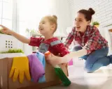 Mama i dziecko bawią się w sprzątanie, ucząc się jak nauczyć dziecko sprzątać. W kartonie są rękawice i płyn.
