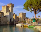 Castello Scaligero sul lago, ideale per vacanze in Lombardia. Barche ormeggiate in un porto pittoresco.