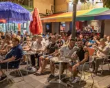 People enjoying drinks at outdoor tables outside gay bars in Sitges, Spain.