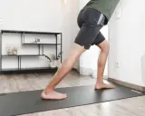 Mann dehnt seine Waden an der Wand, um die Muskeln zu lockern.