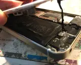 Naprawa iPhone po zalaniu. Widoczna otwarta obudowa, bateria Li-ion i elementy wewnętrzne.
