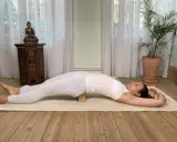 Kvinna i yin yoga-position med en kudde under ryggen. Denna lugna praktik kan stödja din resa mot viktminskning.