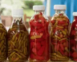 Bouteilles de piments verts et rouges marinés, prêts pour une recette de pickles maison.