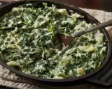 Cremosas espinacas a la crema servidas en una sartén de hierro fundido, con una cuchara lista para servir.