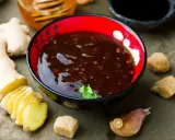 Sos teriyaki przepis: miseczka pełna aromatycznego sosu, obok świeży imbir, czosnek i brązowy cukier. Idealny do dań azjatyckich.