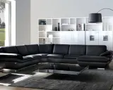 Sofá modular negro de cuero, con mesa de centro de cristal y estanterías blancas. Un diseño de gran dimensión.