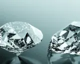 Due diamanti scintillanti, uno rotondo e uno a goccia, riflettono la luce. Uno dei due, un diamante brown, brilla con sfaccettature perfette.