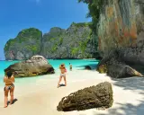 Två personer njuter av det turkosa vattnet och de dramatiska klipporna vid Maya Bay, Thailand.