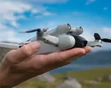 Eine Drohne liegt in einer Hand. Der Abstand zur Autobahn ist groß, die Natur ist im Hintergrund zu sehen.