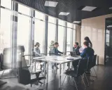 Zespół omawia strategię AML przy dużym stole w sali konferencyjnej z widokiem na miasto.