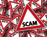Viele rote Dreiecke mit der Aufschrift "SCAM" stapeln sich. Vorsicht vor der aktuellen Online-Betrugsmasche!