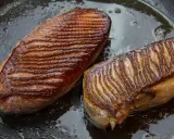 Deux magrets de canard au four, la peau grillée et dorée, baignant dans leur jus de cuisson sur une poêle.