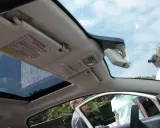 Interior de un Fiat 500 con el techo solar abierto, mostrando el parasol y el espejo retrovisor.