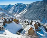Pueblo nevado en los Pirineos, ideal para saber donde ir en el puente de diciembre. Casas de piedra y madera cubiertas de nieve, rodeadas de bosques y montañas.