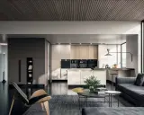 Un elegante appartamento open space moderno con cucina a vista, zona living con divano grigio e poltrona di design.