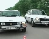 Dwa białe Peugeot 504 jadące obok siebie po wiejskiej drodze.