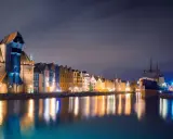 Nocny Gdańsk, Żuraw i zabytkowe kamienice odbijające się w wodzie. Wspaniałe atrakcje pomorskie.