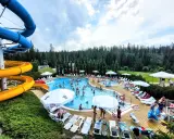 Aqua park Bukowina tętni życiem. Ludzie kąpią się w basenie, zjeżdżają ze zjeżdżalni i odpoczywają na leżakach.