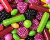Dulces de colores vibrantes: gominolas, caramelos y pastillas. Se intuye que las gominolas están hechas de gelatina, azúcar y saborizantes frutales.