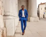 A groom in a bright blue suit and white shirt walks confidently, his brown shoes a perfect complement for a wedding.
