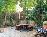 Un angolo relax per il tuo progetto giardino 50 mq: tavolino in legno intagliato, sgabelli, lanterne e un cactus vivace.