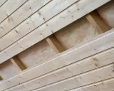 Pose de lambris en bois clair, montrant la structure sous-jacente et l'isolant.