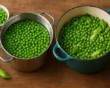 Deux casseroles de pois gourmand en cuisson. L'une contient des pois dans l'eau bouillante, l'autre des pois cuits avec des feuilles vertes.