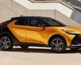 Nowy Toyota C-HR GR w kolorze pomarańczowo-czarnym, z dynamiczną linią nadwozia, zaparkowany przy betonowej ścianie.