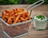 Knusprige Nudel-Chips in einem Metallkorb, daneben ein Glas Dip mit Schnittlauch.