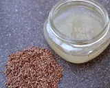 Graine de lin pour rajeunir : une poignée de graines de lin brunes à côté d'un pot en verre rempli d'un gel clair, peut-être un sérum fait maison.