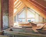 Aménagement des combles : début de la création d'un plancher avec des poutres en bois et des matériaux de construction.