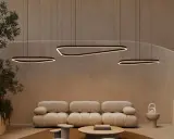 Un salon moderne avec un plafond cathédrale, des suspensions lumineuses organiques, un canapé moelleux et un escalier incurvé.