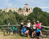 Grupa rowerzystów na tle ruin zamku. Planują noclegi na Szlaku Orlich Gniazd rowerem.