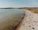 En livlig strand i Halland med många badande och solande människor. Vattnet är klart och inbjuder till lek.