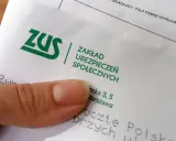 Palec wskazujący na dokumencie ZUS. Pytanie: ile trzeba być na zwolnieniu aby dostać odszkodowanie z ZUS?