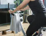 Kobieta w czarnym stroju ćwiczy na rowerze stacjonarnym, spędzając godzinę jazdy na rowerze stacjonarnym w domowym zaciszu.